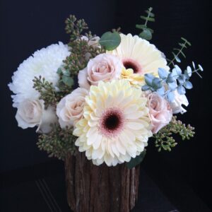 creamy 'Eclaire' gerbera daisies, white commercial mums, roses, and eucaluptus in a wood container