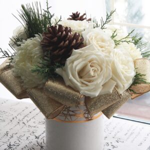 white roses and gold ribbon, with winter green and pinecones in a white vase